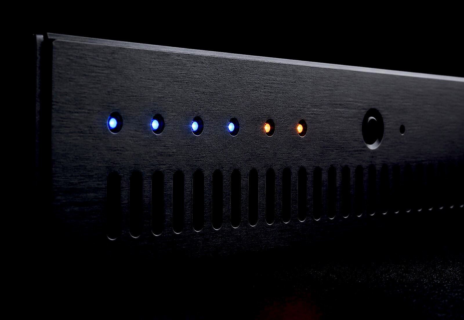 Macro detail of a Xorcom appliance front panel: status LEDs, ventilation slots and brushed metal chassis
