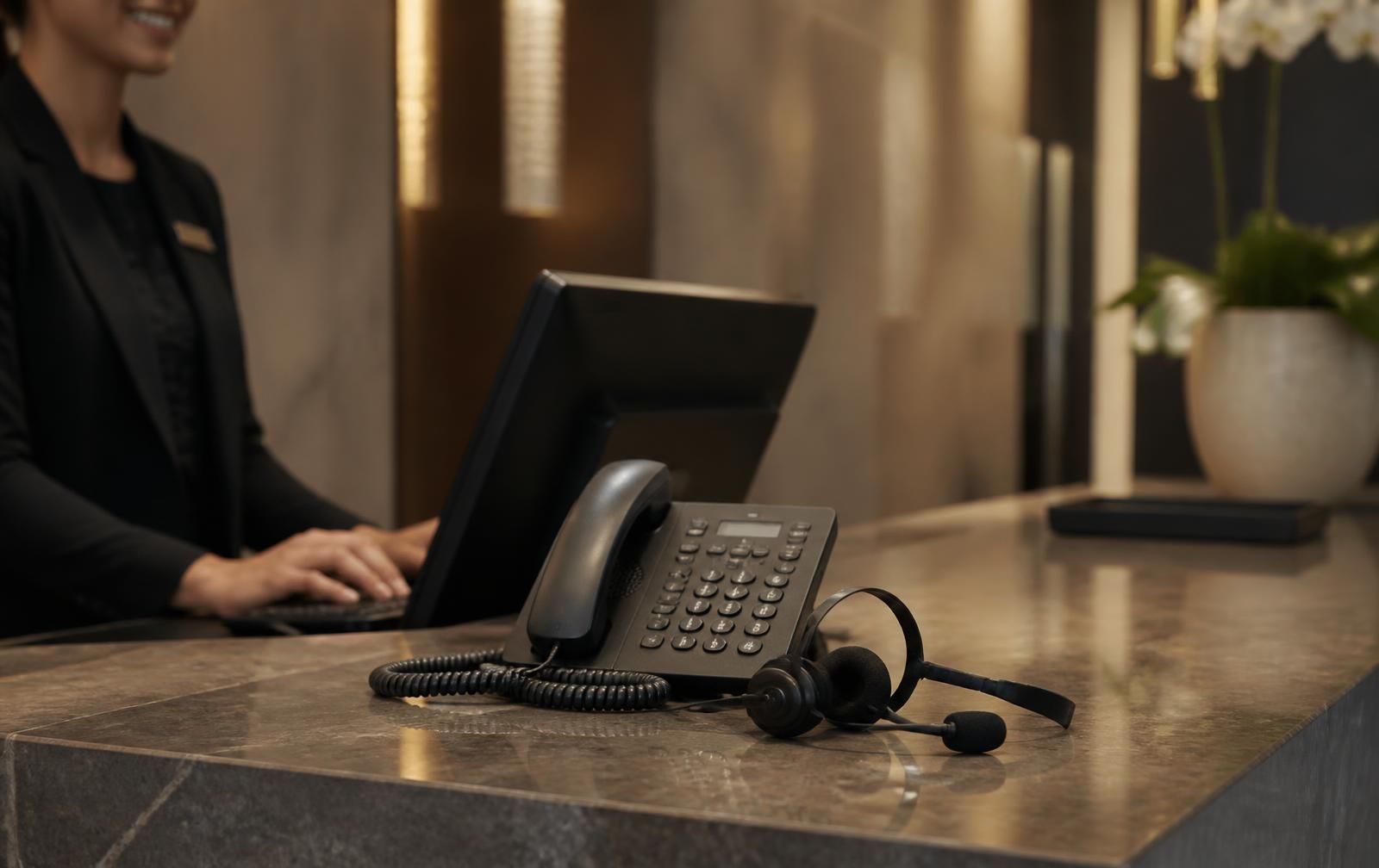 Hotel front desk with a Xorcom business phone in use at reception